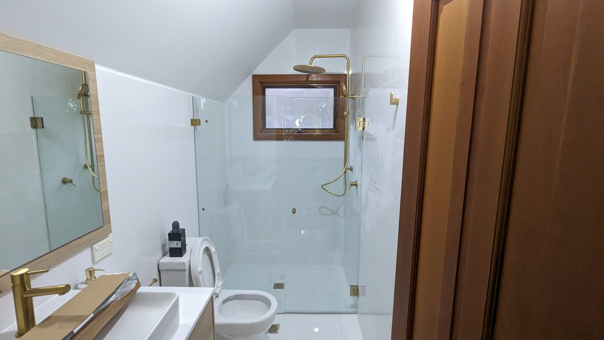 Bathroom renovation with timber door, brass fittings, and tiled walk-in shower in Deakin